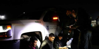Officials interacting with seated individuals at nighttime outdoors