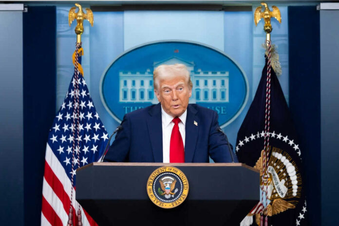 Man speaking at podium with flags in background