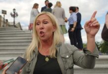 A woman passionately speaking outdoors, surrounded by people and media.