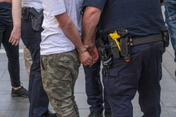 1977146003 Person handcuffed by police on the street