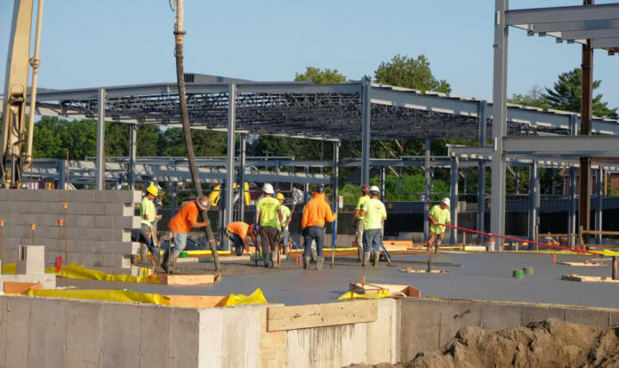 Construction workers laying concrete at building site
