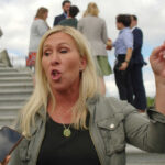 Woman gesturing and speaking outside on steps.