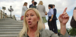 Woman gesturing and speaking outside on steps.