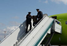 Explosive Giants’ Plane Incident: Coach OUT! Police officers escorting a passenger down the stairs from an airplane