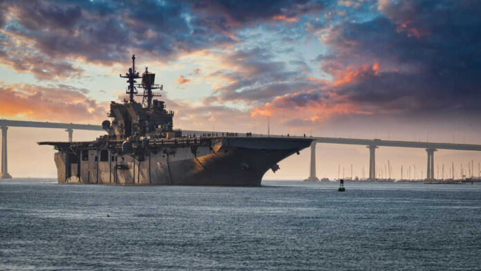 shutterstock_1636824865 Aircraft carrier near bridge under colorful sunset sky