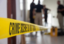 SHOCKING Security Failure Enables Brown Massacre Yellow crime scene tape with blurred figures in the background