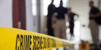 Yellow crime scene tape with blurred figures in the background