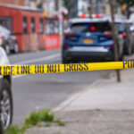 Police tape blocking street with parked cars