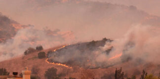 Wildfire approaching residential area with smoke rising