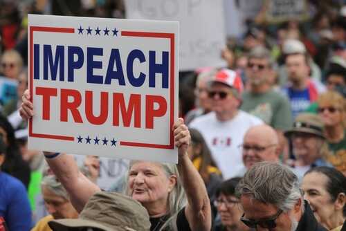 A crowd at a protest holding a sign that says IMPEACH TRUMP